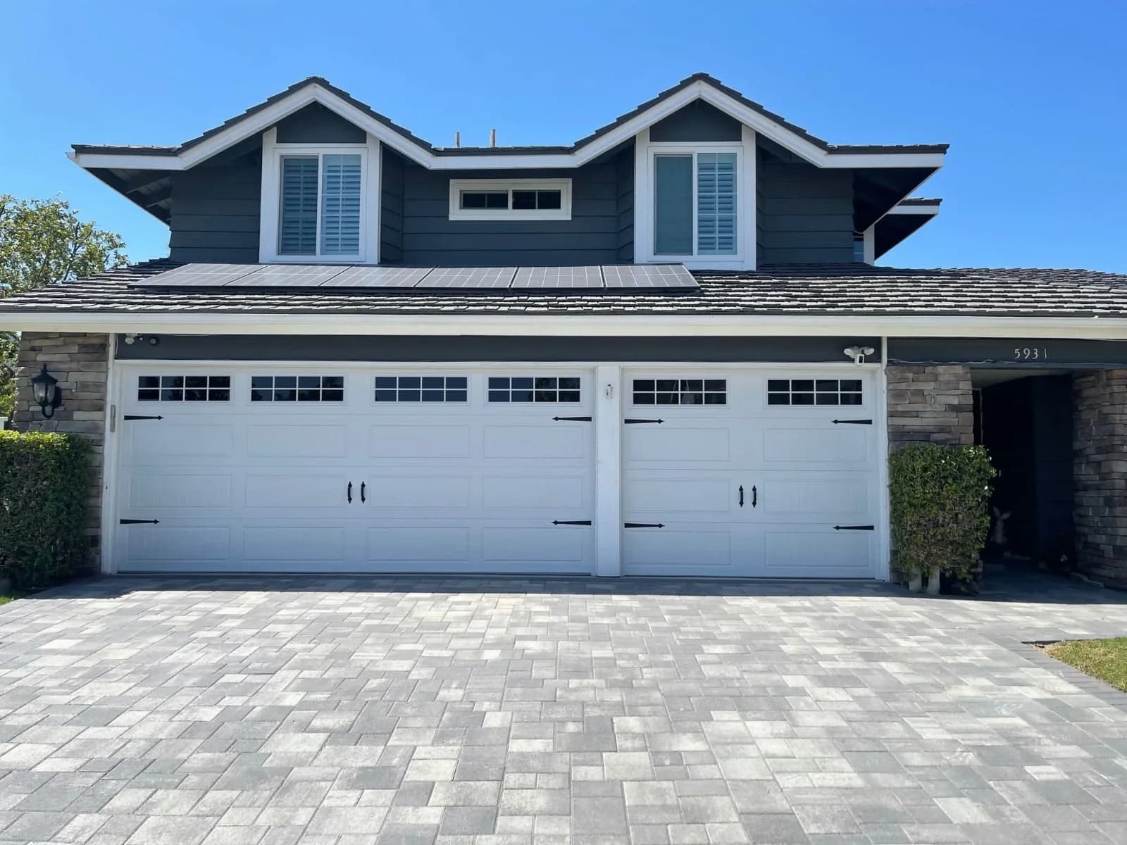 Three-car garage with carriage doors and a paver driveway