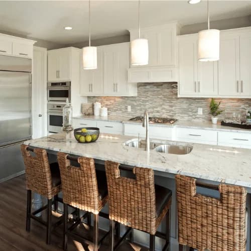 Example: white kitchen with a stone island, pendant lights and rattan stools